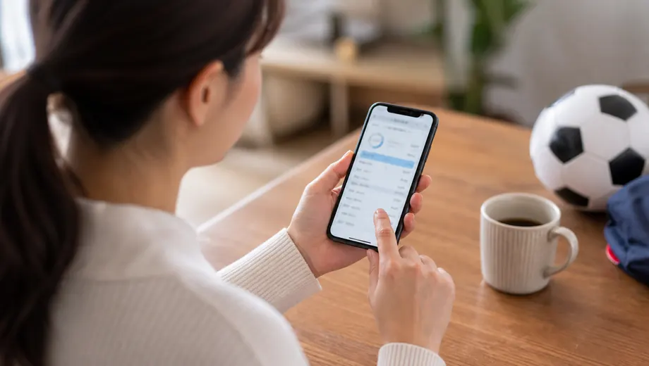 自宅でスマートフォンの月謝明細を確認する保護者
